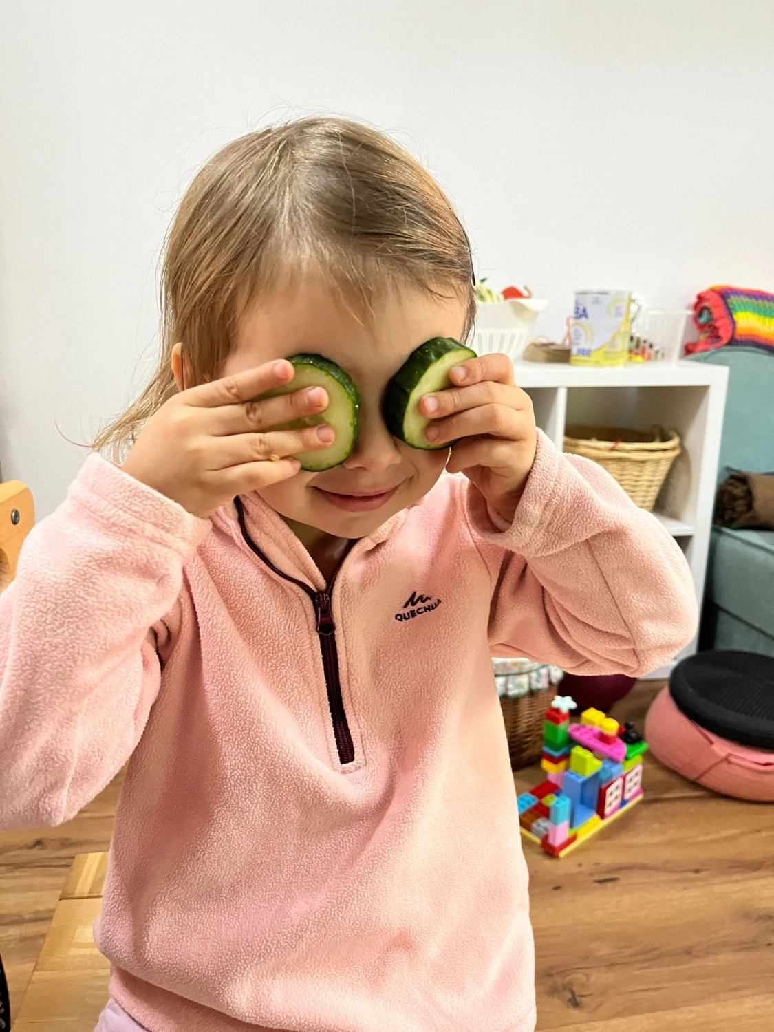 Kleines Mädchen spielt mit der Gurke von Tagesmutter